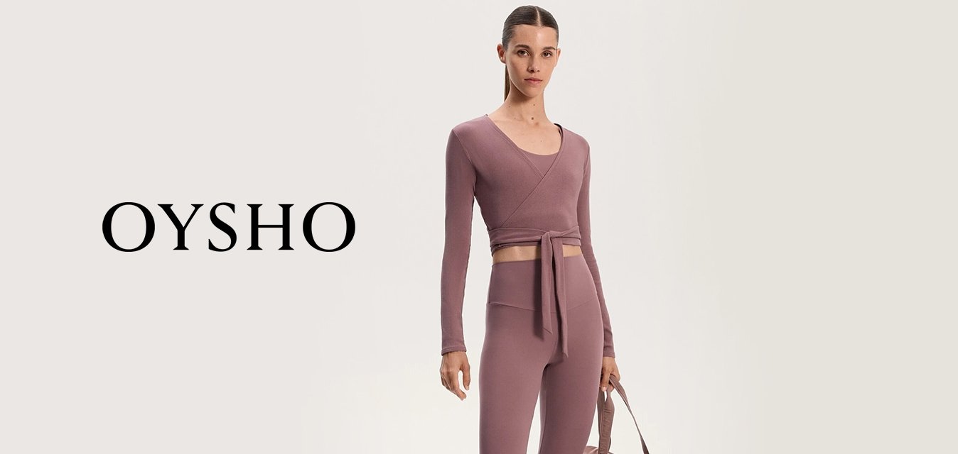 Fialový sportovní crop top se zavazováním, v kombinaci s legínami s vysokým pasem; modelka drží odpovídající taupe sportovní tašku; tenisky s krémovými akcenty.