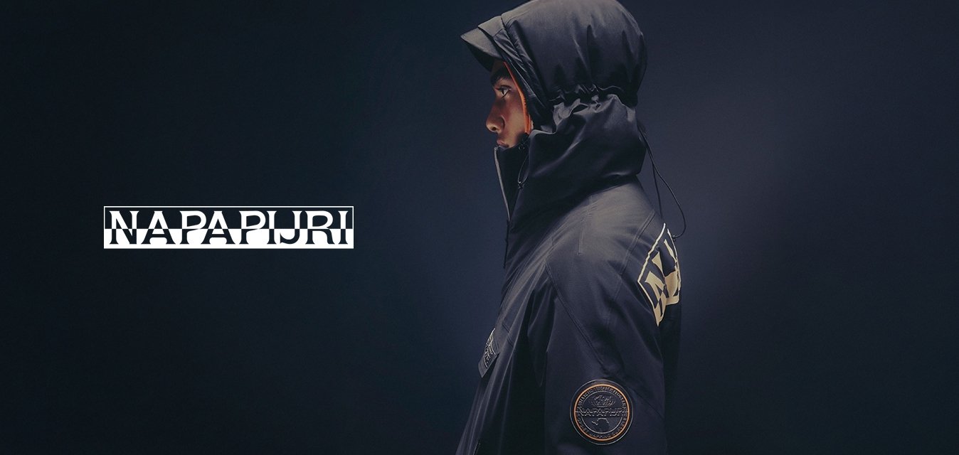 Osoba v profilu, která má na sobě tmavou bundu s kapucí a kšiltovkou, na rukávu kulatou nášivku a na zádech velký nápis.