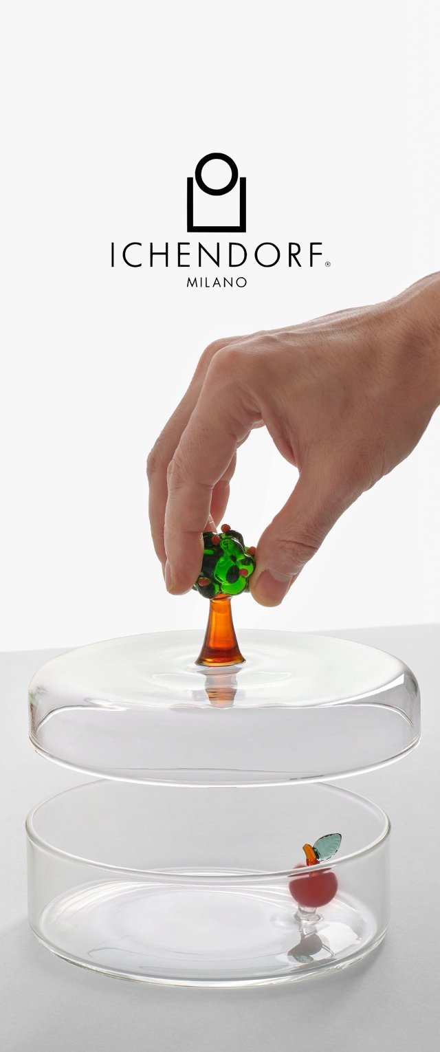 Käsi nostaa lasikupua, jossa on puunmuotoinen kahva, paljastaen pienen lasisen omenan kirkkaan pyöreän säiliön sisällä, yläpuolella Ichendorf Milano -logo.