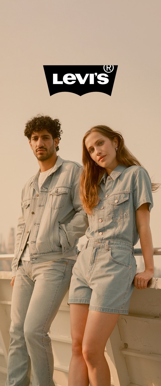 Ein hellblaues Jeansjackett und -hosen an einem Mann; ein hellblaues Jeansoverall an einer Frau. Beide Outfits weisen ein klassisches Design und subtile Nahtdetails auf.