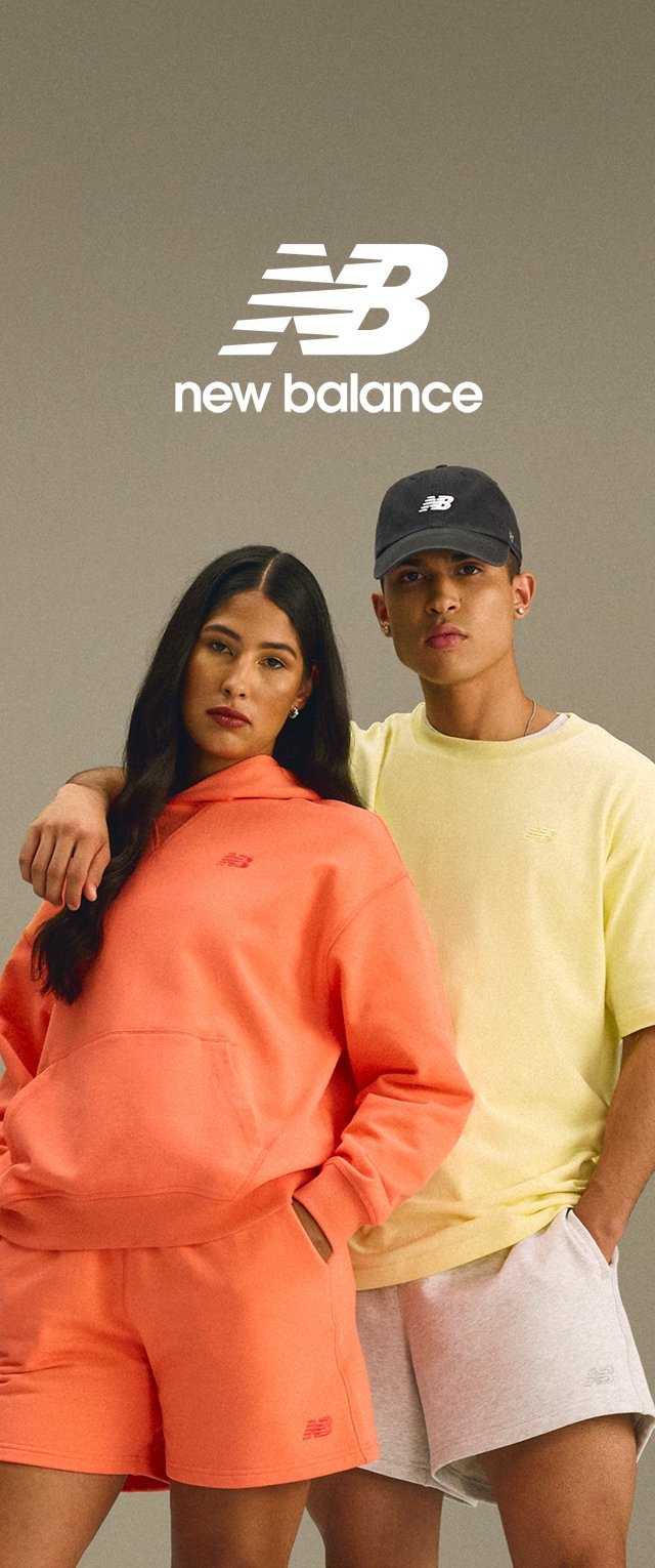 Zwei Models posieren in lebhaften Sportbekleidungen. Eine trägt einen orangefarbenen Sweatshirt und Shorts, während die andere ein gelbes T-Shirt und graue Shorts trägt.