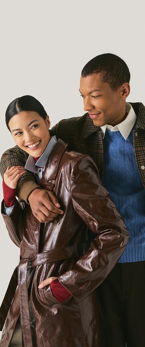 Brun læder trench coat med en bælte i taljen. En blå kabelstrikket sweater og røde ærmer i kontrast bæres under den.