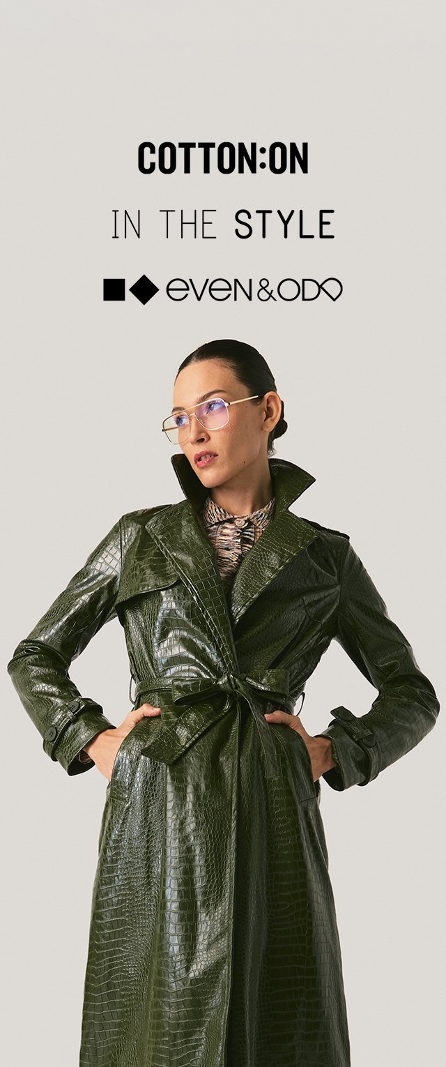 Trench-coat vert en similicuir avec texture crocodile, col oversize et fermeture à nouer à la taille. Le modèle porte des lunettes.