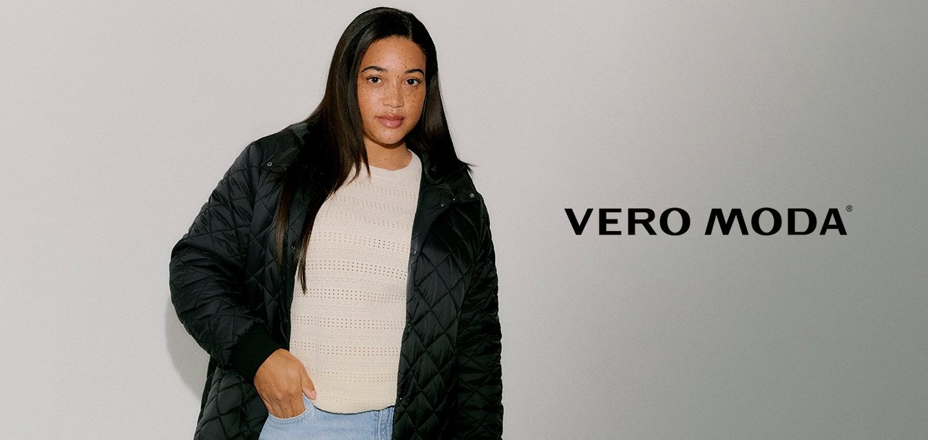 Černý prošívaný dlouhý kabát s bočními kapsami, žebrovanými manžetami a zapínáním na zip, nošený přes krémový pletený top a světle modré džíny.