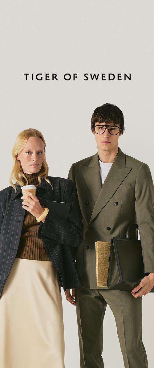 Twee modellen in op maat gemaakte pakken, de ene met een koffiebeker en notitieboekje, de andere met een aktetas en krant, met daarboven de tekst "TIGER OF SWEDEN".