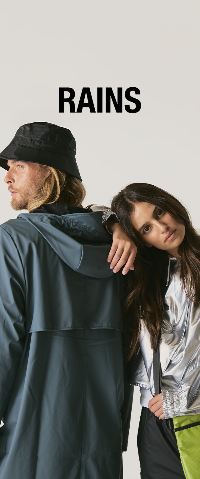 Two people wear modern rain jackets. One jacket is teal matte fabric with a hood; the other is shiny silver. A bucket hat completes the look.