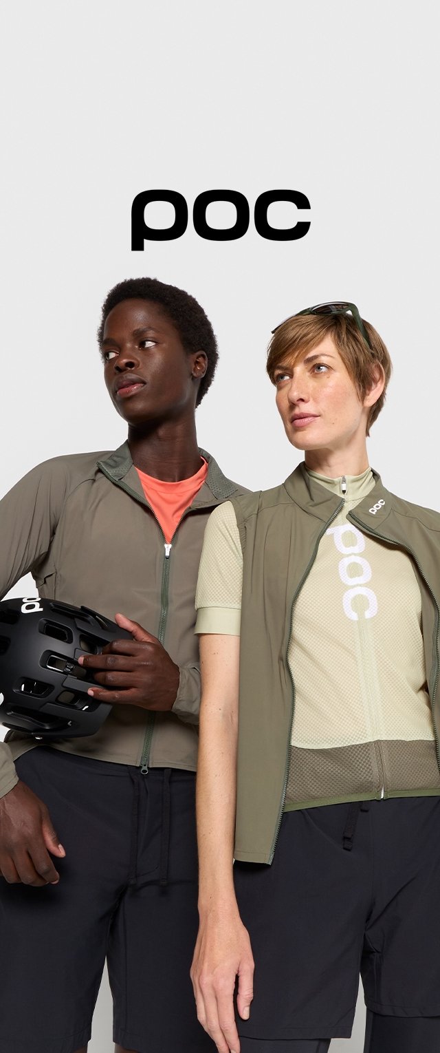 Dos modelos visten ropa de ciclismo de POC. Uno lleva una chaqueta verde oliva y una camiseta roja, y el otro lleva un chaleco beige sobre una camiseta de malla.