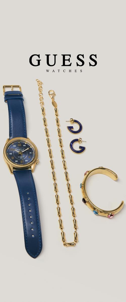 Reloj de oro con correa de cuero azul, collar de cadena dorada, pendientes de aro azules y pulsera de puño dorada con piedras de colores sobre un fondo claro.
