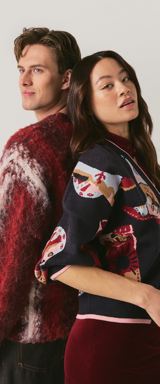 Mann und Frau Rücken an Rücken, tragen bunte Pullover und blicken in entgegengesetzte Richtungen vor einem schlichten hellen Hintergrund.