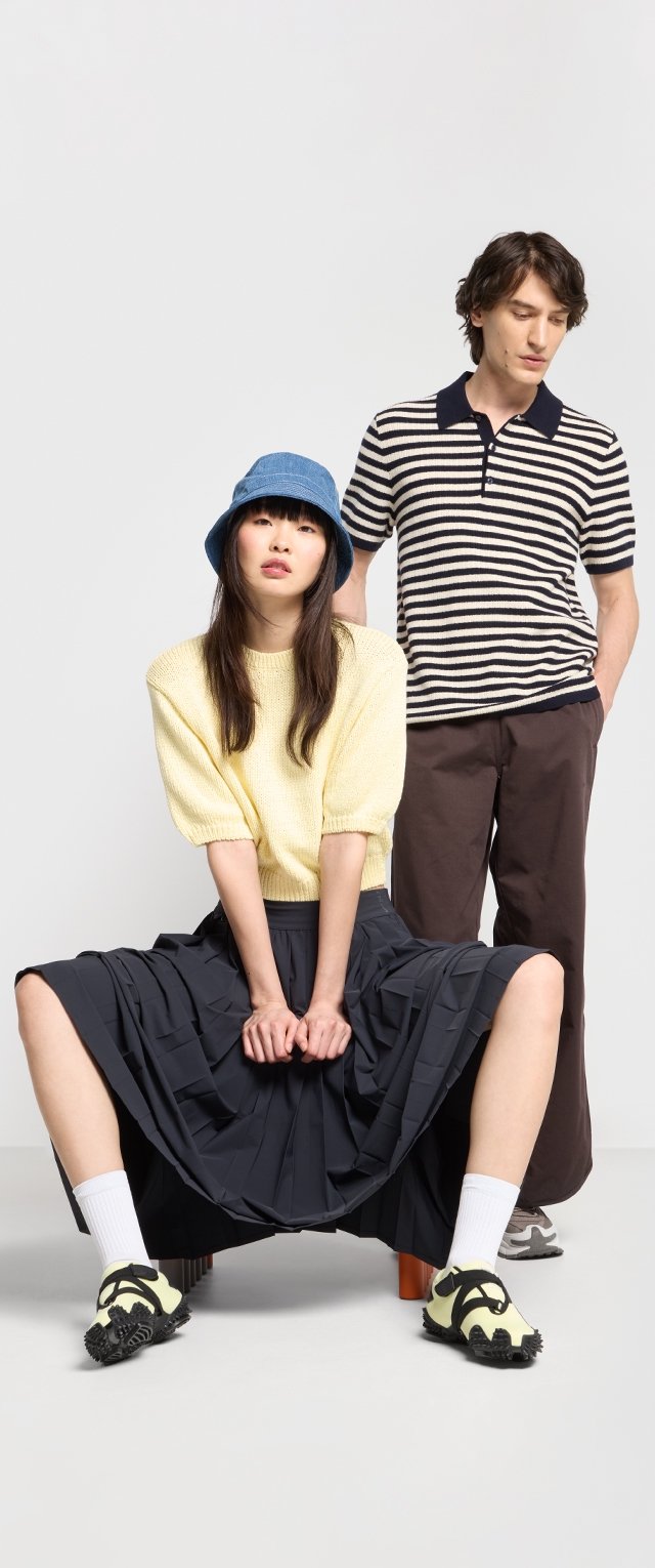 Dos modelos posan; uno con un suéter de punto amarillo y una falda navy plisada, el otro con una camiseta de rayas y pantalones marrones. El calzado incluye acentos amarillos.
