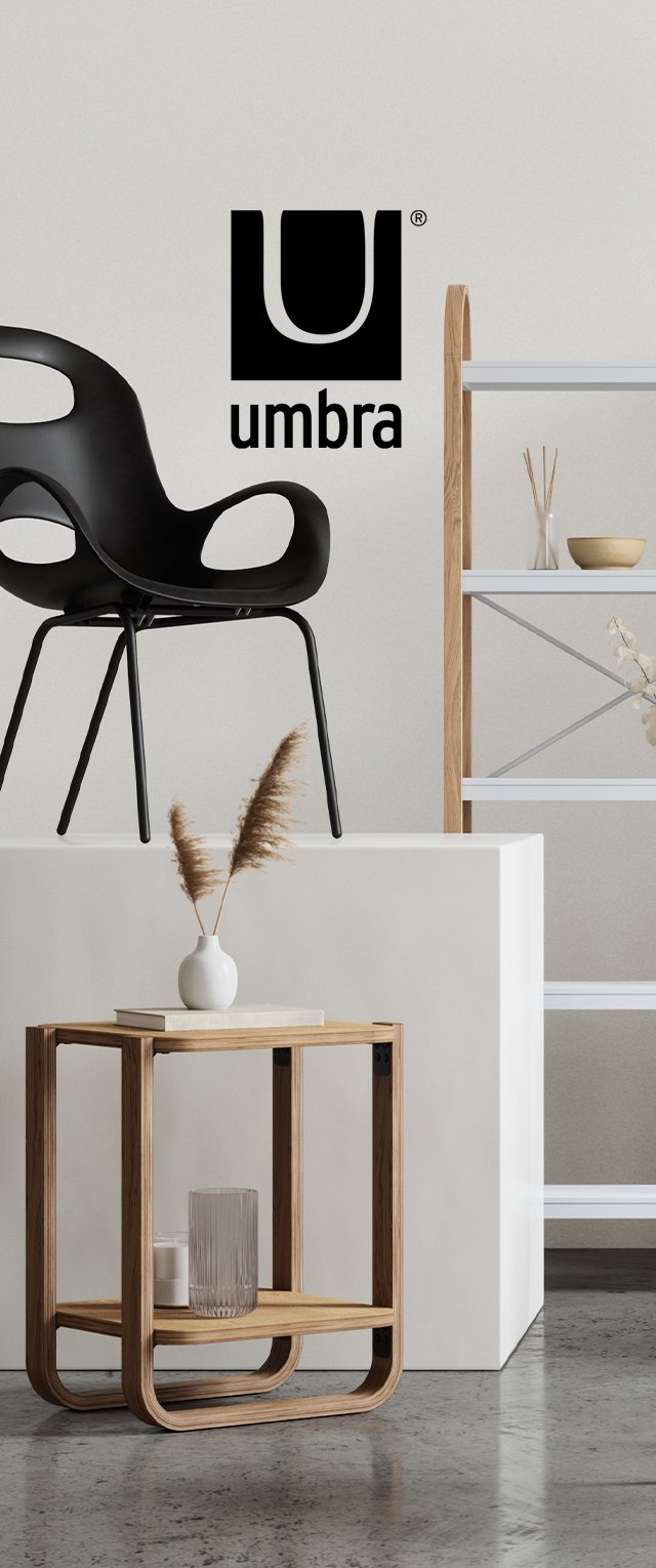 Chaise en plastique noir aux courbes lisses sur un piédestal blanc. Table d'appoint en bois aux bords arrondis portant un verre et une bougie. Fond clair.