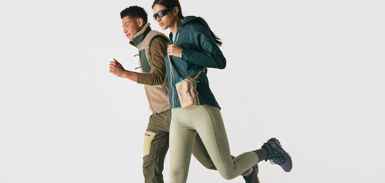 Dva lidé oblečení v outdoorovém sportovním oblečení a teniskách, běžící vedle sebe na jednoduchém bílém pozadí.