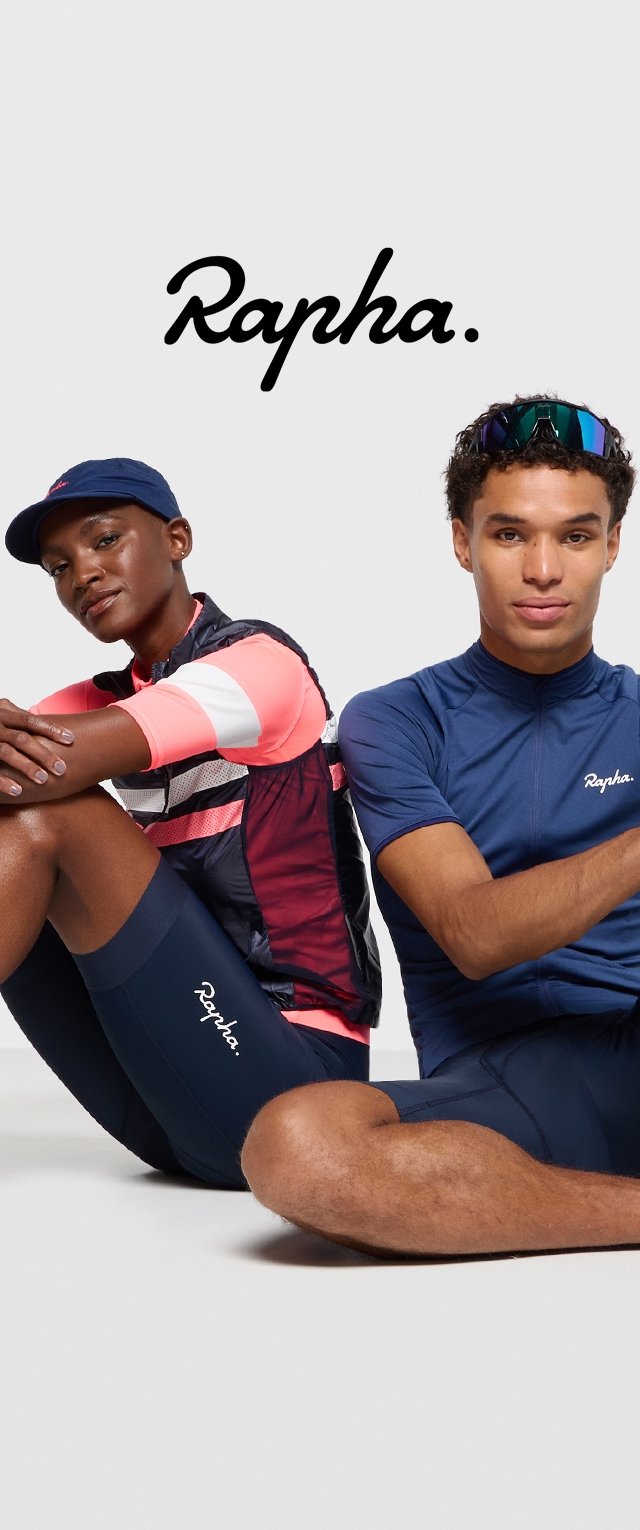 Ropa de ciclismo Rapha que presenta un chaleco a rayas rosas con acentos negros y pantalones cortos de jersey azul marino. Dos modelos sentados muestran conjuntos distintos.