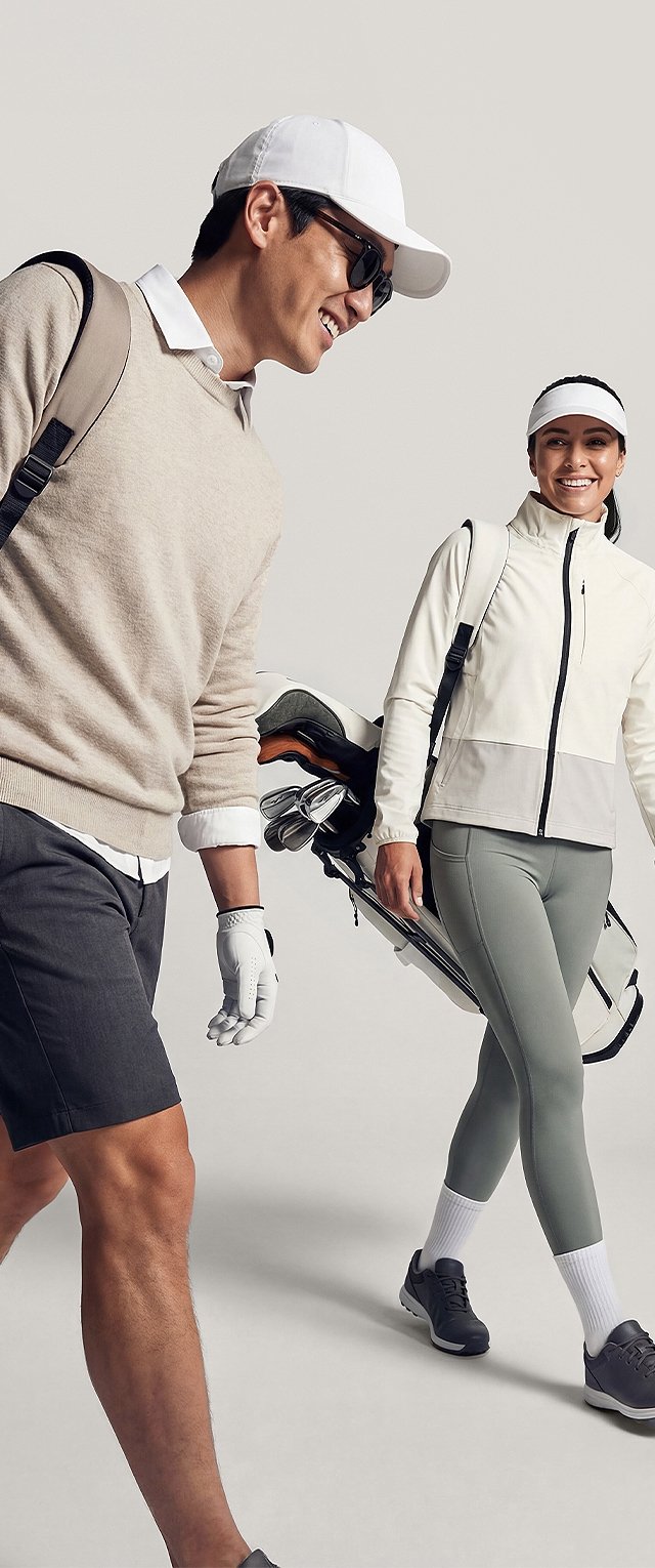 Hombre con gafas de sol y gorra y mujer con visera llevan bolsas de golf, vestidos con ropa deportiva casual para golf, sonriendo y caminando.