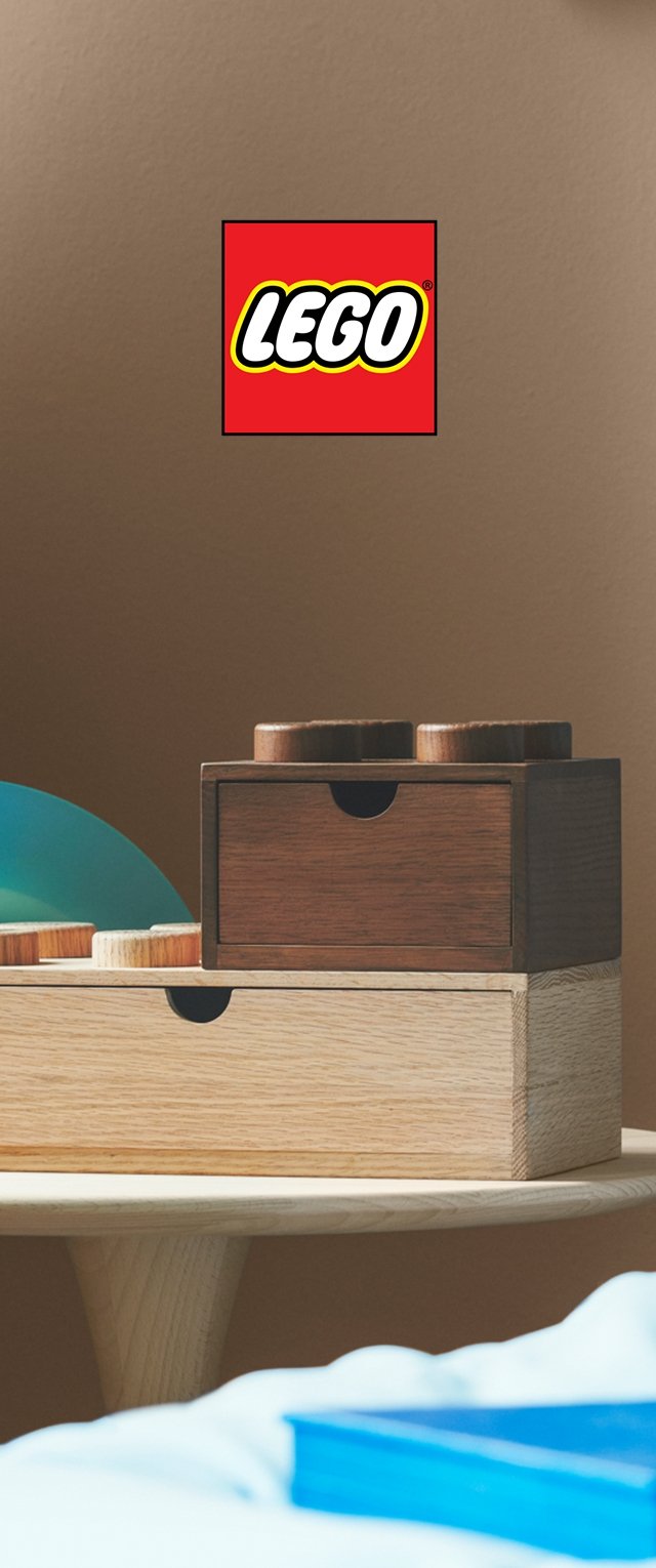 Cajas de madera apiladas en tonos claros y oscuros con tapas redondeadas, con un logo de LEGO encima y un objeto azul curvado al lado.