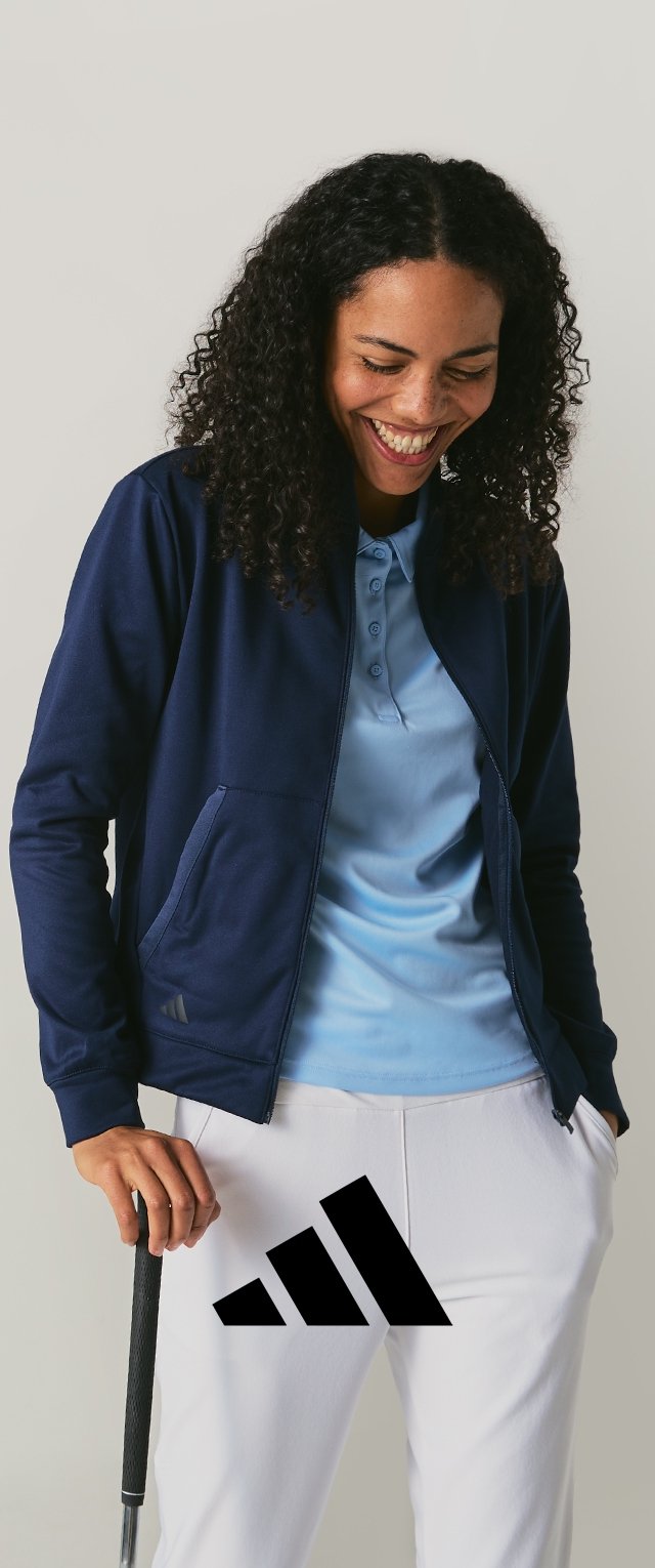 Tumši zils rāvējslēdzēja džemperis pārsvītrots pāri gaiši zilam polo, kombinēts ar baltām biksēm. Vienā rokā tiek turēts golfa klubs; biksēs redzams Adidas logo.