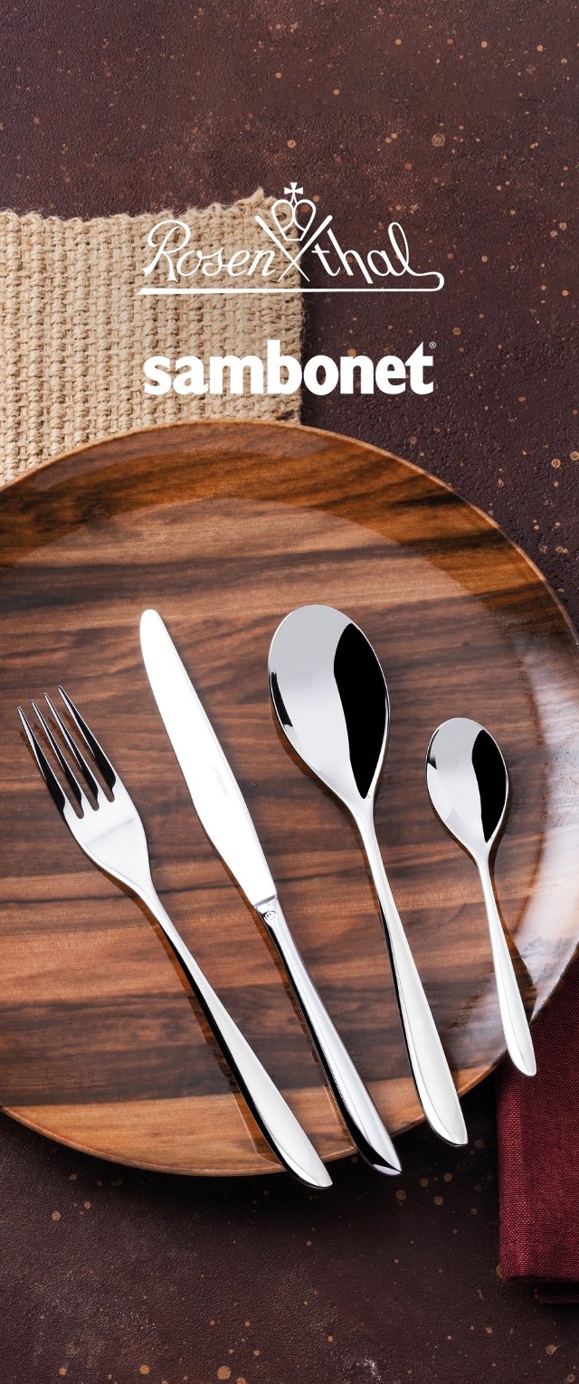 Juego de cubiertos de acero inoxidable sobre un plato de madera: un tenedor, un cuchillo, una cuchara grande y una cucharita con superficies pulidas y un diseño elegante.