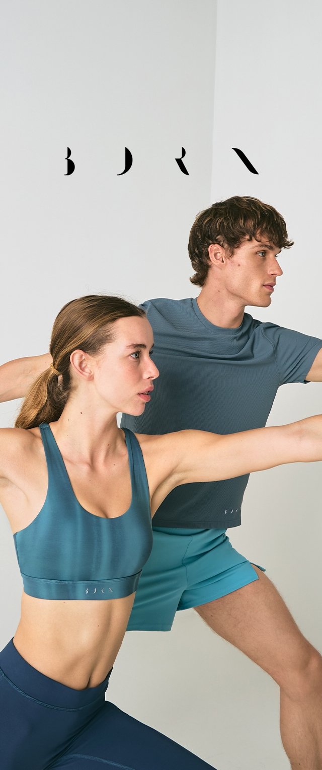 Un par de personas realizando una postura de yoga, vestidas con ropa deportiva color teal. La mujer lleva un sujetador deportivo ajustado y leggins; el hombre lleva una camiseta ajustada y pantalones cortos.