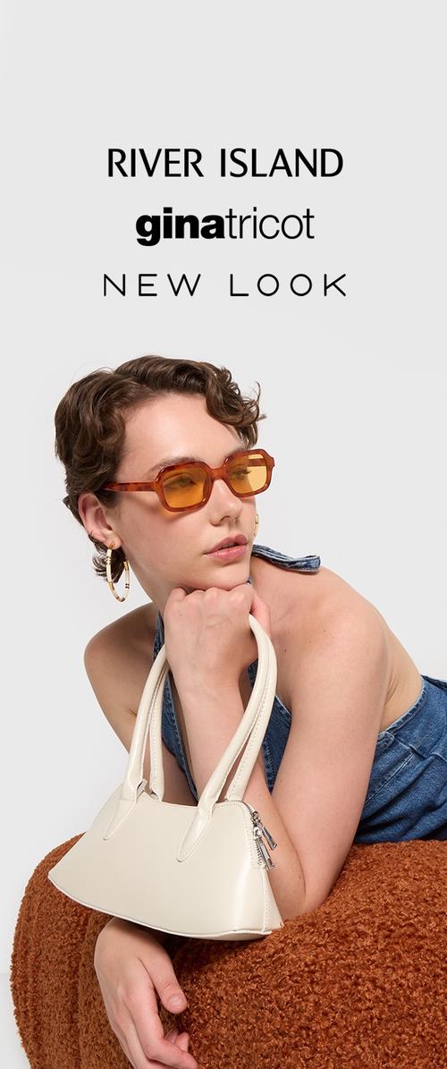Bolso blanco con diseño estructurado y doble asa, acompañado de gafas de sol con tono naranja. El modelo viste un atuendo de denim azul frente a un suave fondo marrón.