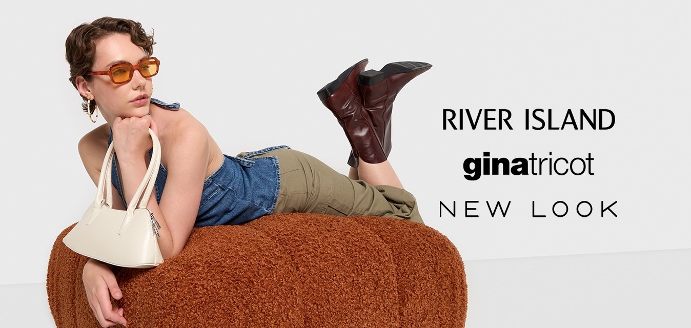 Bílá kabelka s dvěma krátkými uchy, denimová blůza, olivově zelené kalhoty, oranžové sluneční brýle a hnědé kožené kotníkové boty, na hnědém texturovaném povrchu.