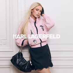 Žena s dlouhými blond vlasy nosí růžovou bundu s nášivkami, černou sukni, černou rukavici a drží černou kabelku se zlatým řetízkovým popruhem.