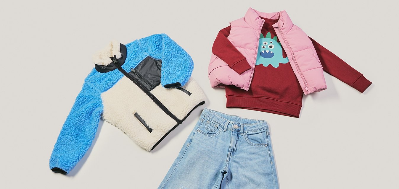 Modrá a krémová fleecová bunda, růžová vatovaná vesta, vínově červená mikina s potiskem, roztrhané světle modré džíny. Různé textury a barvy.