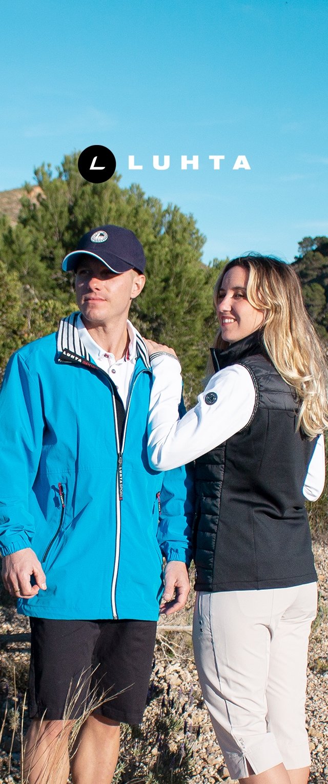 Hombre con chaqueta azul y gorra y mujer con chaleco negro y pantalones blancos están en el exterior rodeados de árboles y cielo azul, con el logo de Luhta arriba.
