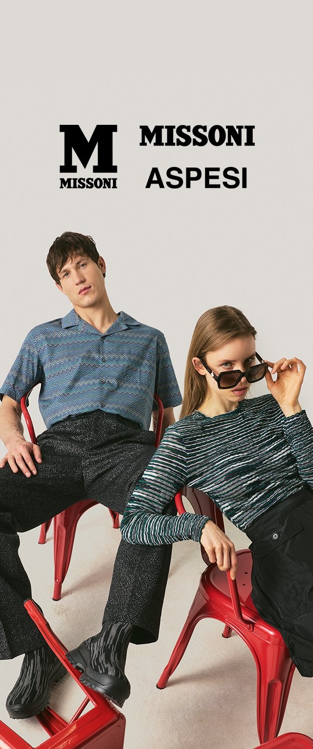 Zwei Models sitzen auf roten Metallstühlen, tragen gemusterte Oberteile und dunkle Hosen, mit den Markenlogos "MISSONI" und "ASPESI" darüber.