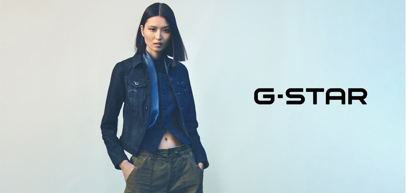 Džínová bunda s přiléhavým střihem, tmavě modrá barva, přední kapsy, v kombinaci s modrou košilí na knoflíky a olivově zelenými kalhotami.