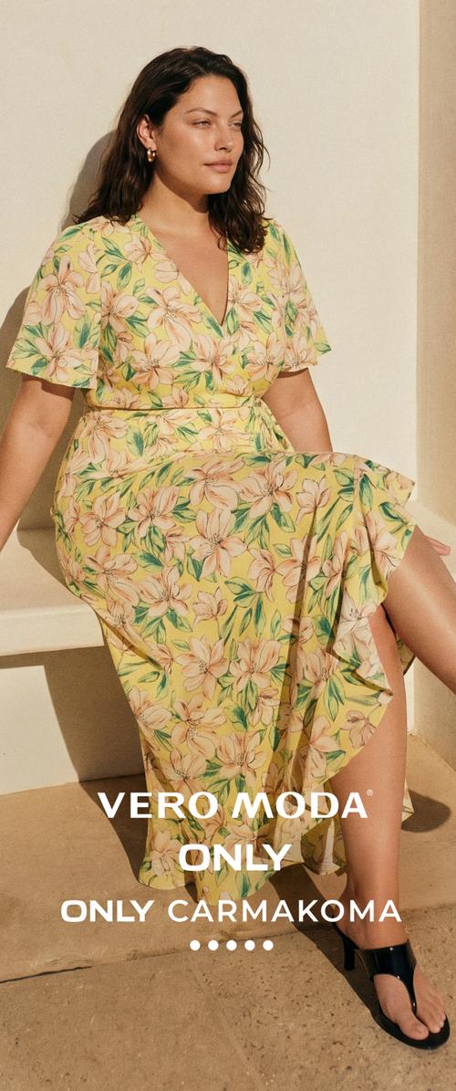 Frau mit mittellangen dunklen Haar, die goldene Creolen und ein gelbes, geblümtes Wickelkleid trägt und auf einer Stufe im natürlichen Licht sitzt.