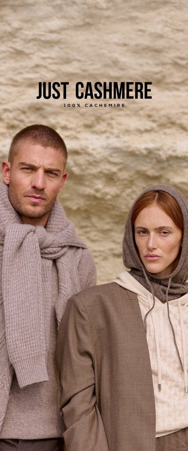 Hombre y mujer vestidos con ropa de cashmere marrón y beige, de pie frente a una pared texturizada beige con el texto "Just Cashmere" arriba.