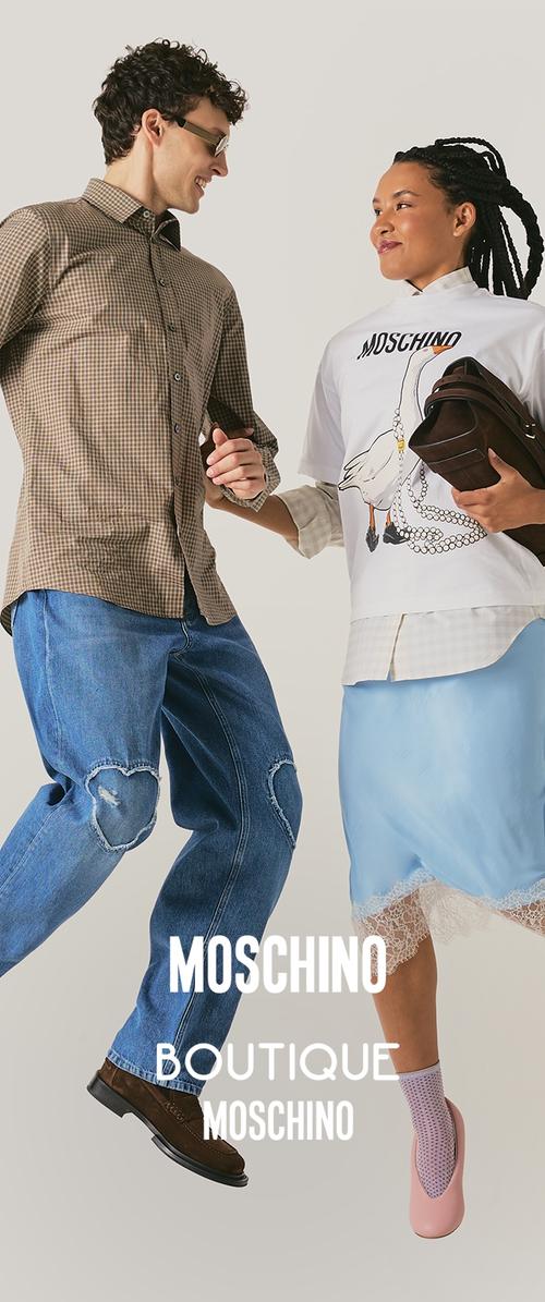 Hombre sonriente con camisa a cuadros y vaqueros y mujer con camiseta Moschino, falda azul, sosteniendo bolso, saltando sobre fondo beige.