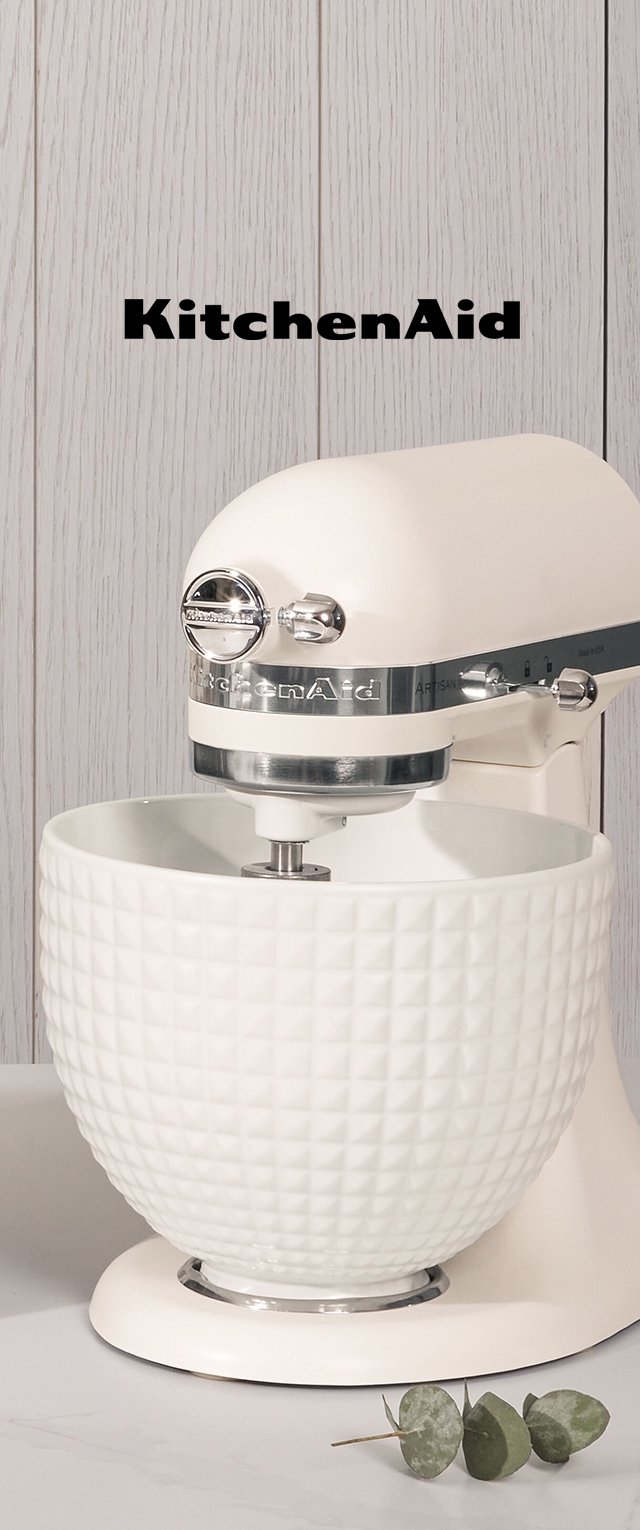 KitchenAid köksmaskin i krämfärg med en texturerad skål, kromade detaljer och en rundad design. Basen är slät med synliga kontroller.