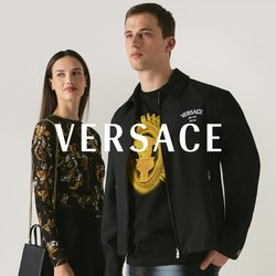 Muž a žena stojí vedle sebe, oba mají oblečení s černozlatým vzorem; žena drží černou kabelku se zlatým řetízkem.