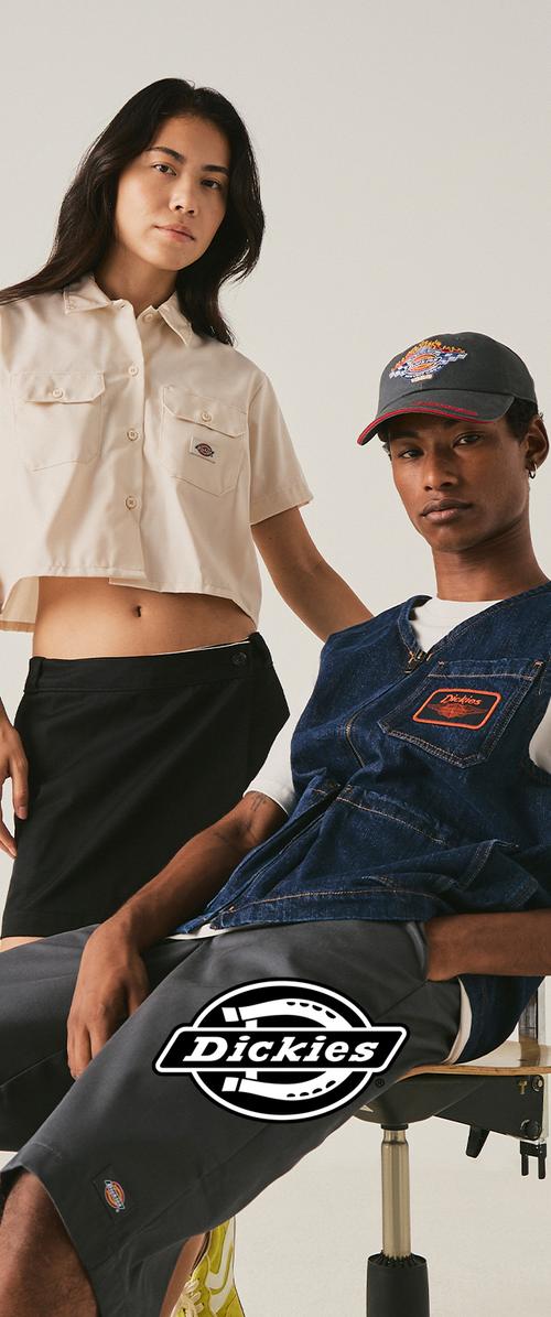 Two models wear Dickies clothing: one in a cropped beige shirt and black skirt, the other in a blue vest, cap, and gray shorts.