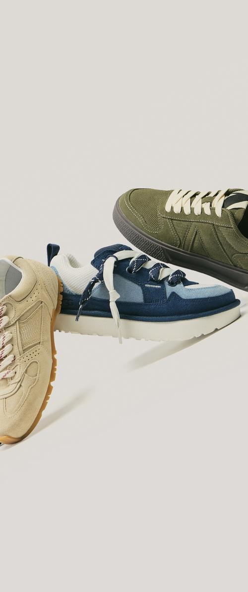 Trois paires de chaussures de sport : daim beige avec semelle en caoutchouc, mesh bleu marine et bleu clair avec lacets, tissu vert olive avec lacets blancs et design texturé.
