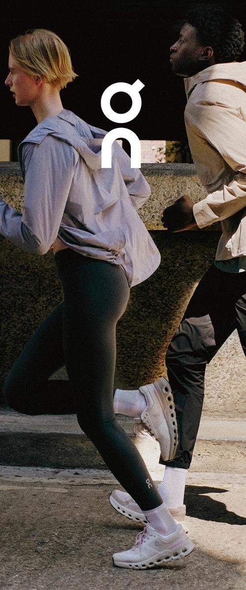 Deux personnes courent en plein air, portant des vêtements de sport et des chaussures de course blanches avec des sangles velcro en plein jour.