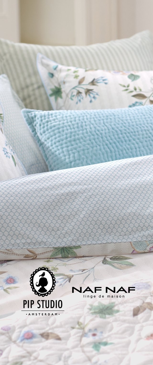 Una variedad de cojines decorativos sobre una colcha acolchada. Están presentes telas con textura en azul claro, patrones florales y diseños geométricos sutiles.