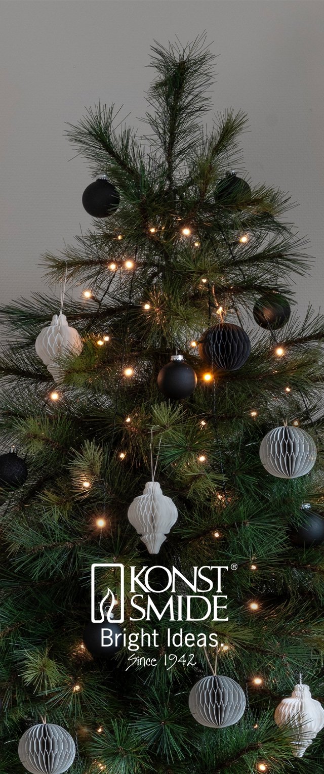 Árbol de Navidad artificial con follaje verde, decorado con adornos esféricos en blanco y negro y decoraciones de panal. Incluye luces de cadena de color blanco cálido.