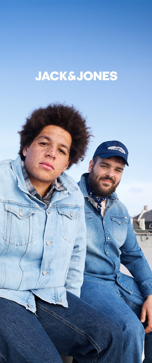Jeansjacken und Jeans in hellblau und mittelblau. Eine Jacke hat große Taschen; beide Modelle tragen lässige Hemden. Heller Himmel im Hintergrund.