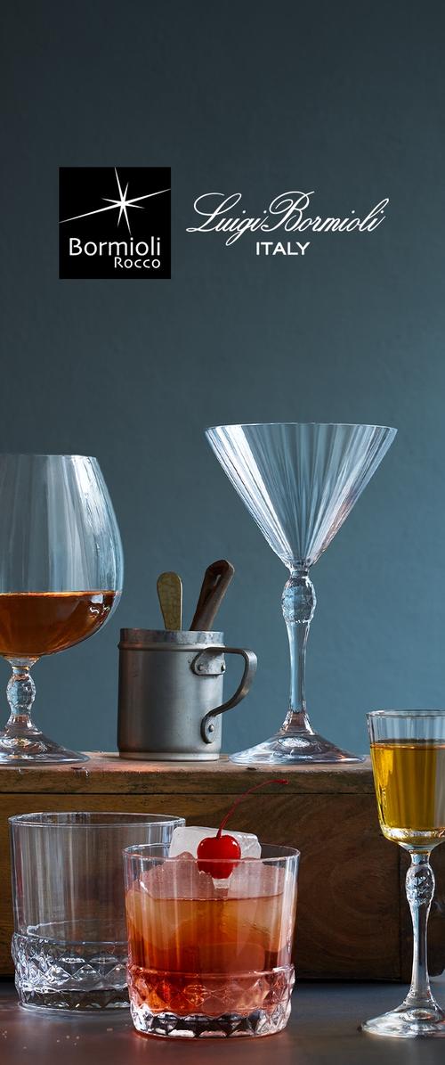 Przezroczyste kryształowe naczynia obejmują szeroką szklankę z dużą misą, wysoką szklankę do martini oraz krótką tumbler z wiśnią. W zestawie znajduje się metalowy shaker i drewniane mieszadełka.