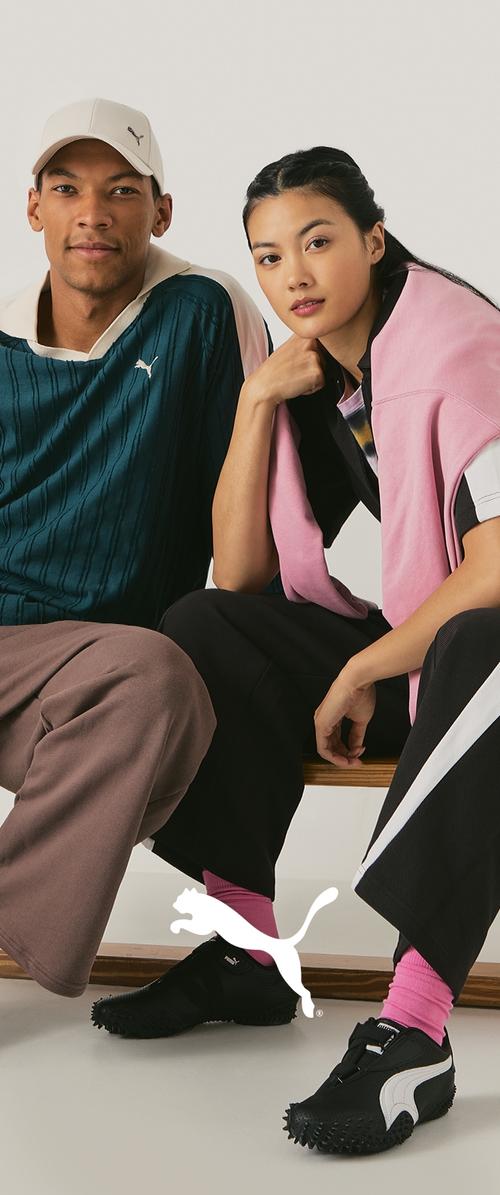 Ropa de Puma en tonos azul y rosa; hombre con camiseta texturizada y gorra, mujer con capas en colores combinados. Ambos llevan zapatos negros con acentos de logo blanco.