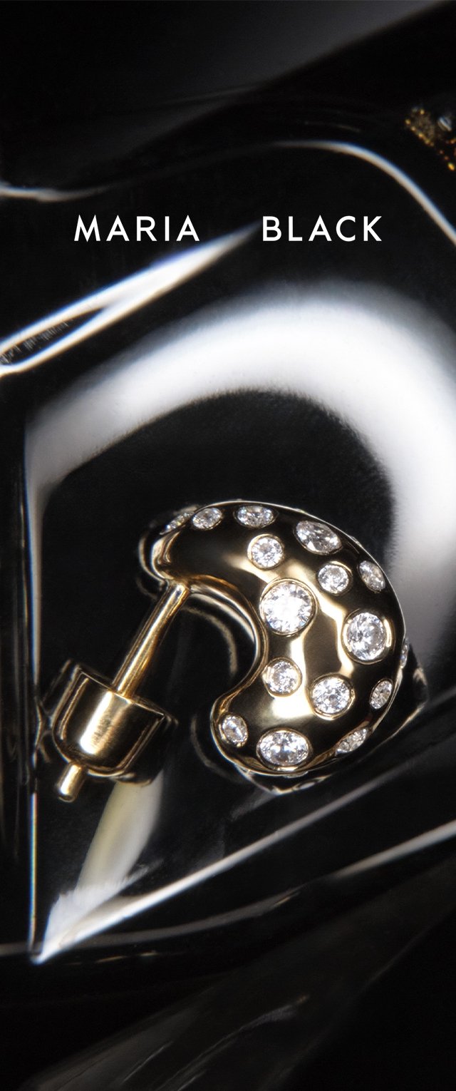 Pendiente dorado en forma de media luna adornado con múltiples piedras preciosas blancas redondas sobre una superficie negra brillante con el texto "MARIA BLACK" encima.