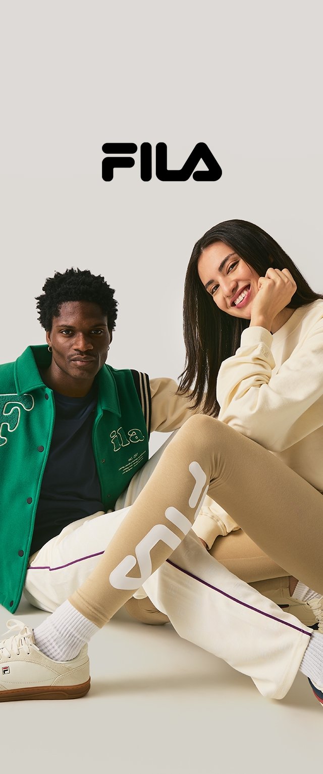 Chaqueta verde FILA con bordado blanco, camisa azul marino, leggings beige con logo y zapatillas blancas; fondo neutro. Logo de texto negro arriba.