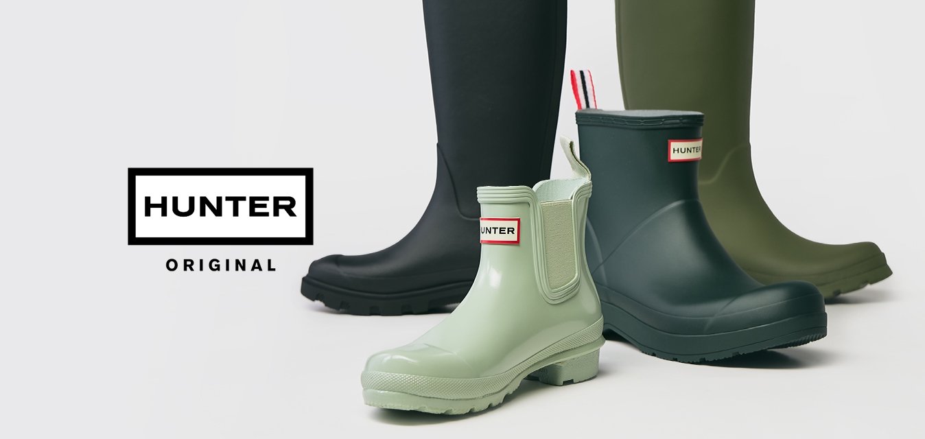 Čtyři páry gumových bot Hunter v černé, tmavě zelené, světle zelené a námořnické modré, uspořádané na bílém pozadí.
