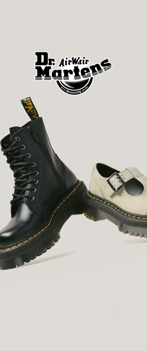 Bota negra de cuero con cordones y zapato Mary Jane beige con suelas gruesas con costuras amarillas, posicionados uno al lado del otro, con el logo de Dr. Martens arriba.