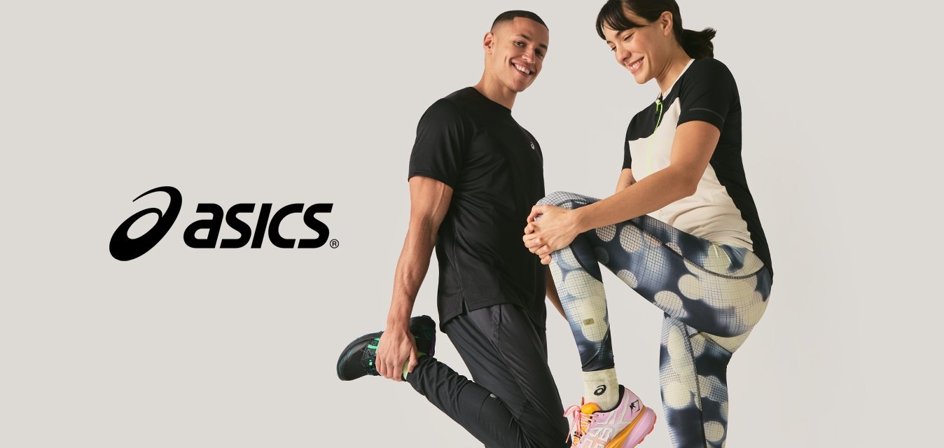 Muž a žena v sportovním oblečení se usmívají při protahování nohou na jednobarevném světlém pozadí.