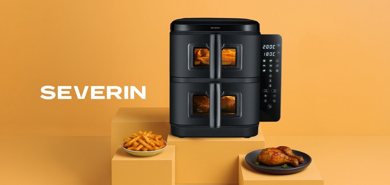 Černá fritéza s horkým vzduchem se dvěma přihrádkami, digitální ovládání na boku, umístěna na světlém oranžovém pozadí, s hranolkami a kuřecím masem na talířích.