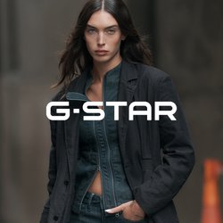 Žena s dlouhými tmavými vlasy, má na sobě rozepnutou tmavou bundu přes úzké džíny a tmavé sako, stojící ve městě.