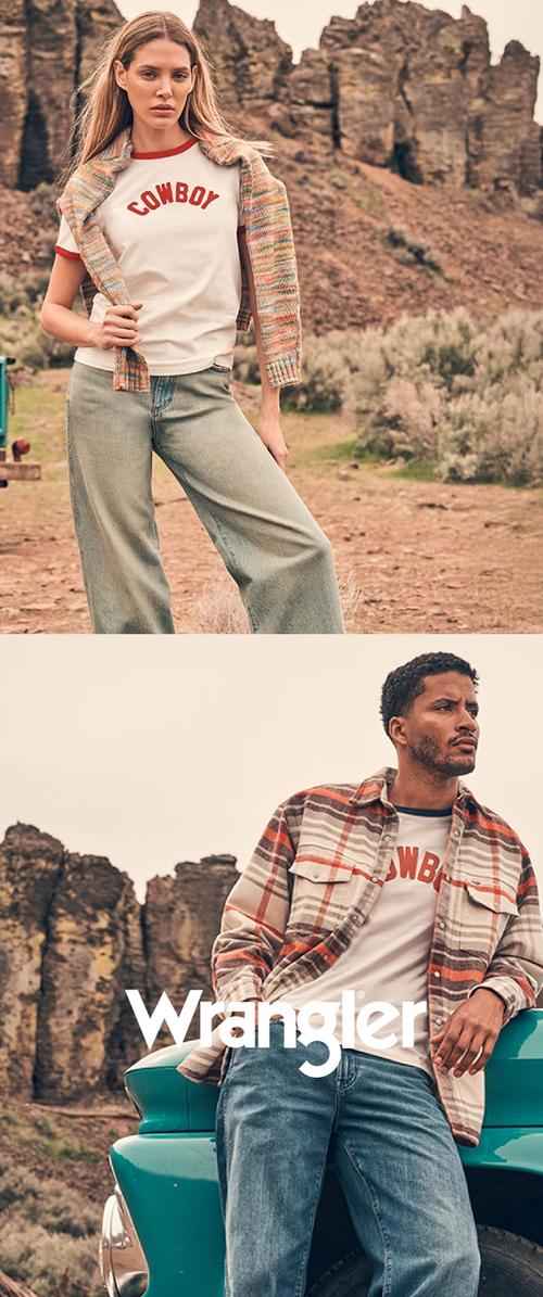 Woman wearing "Cowboy" shirt and cardigan stands in desert; man wearing plaid shirt and "Cowboy" shirt leans on vintage turquoise truck nearby.
